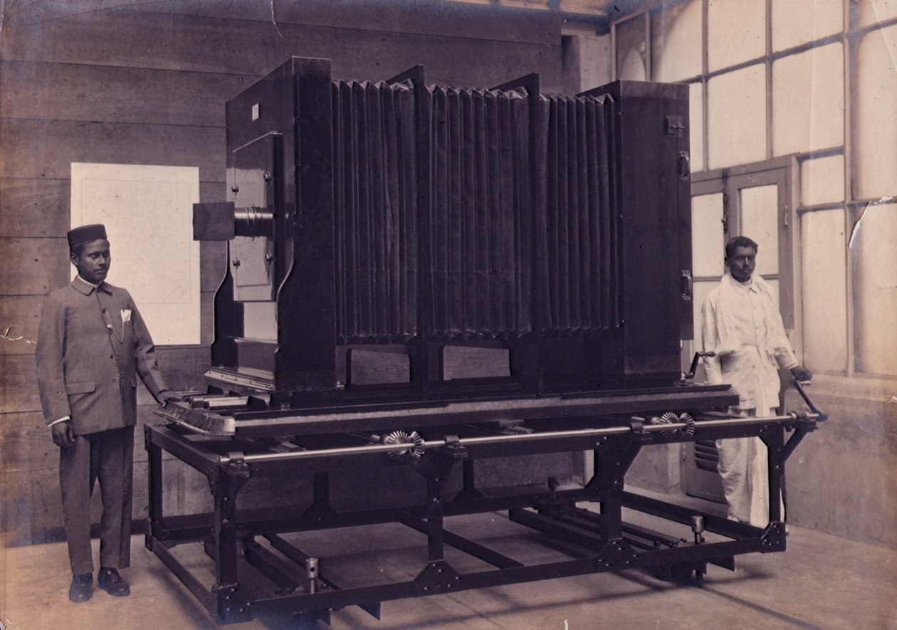 To indiske assistenter som står ved siden av det massive kameraet i Photographic Department of the Survey of India, ca. 1911 (bilde) av English Photographer