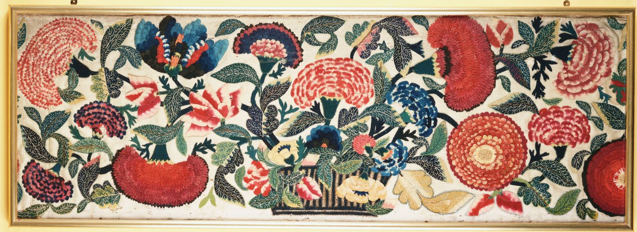Et filt- og applikasjonspanel med broderte silkehøydepunkter som viser nelliker, tulipaner og andre blomster som renner over fra en kurv mot en malt ull i elfenben, ca. 1730-40 av English School