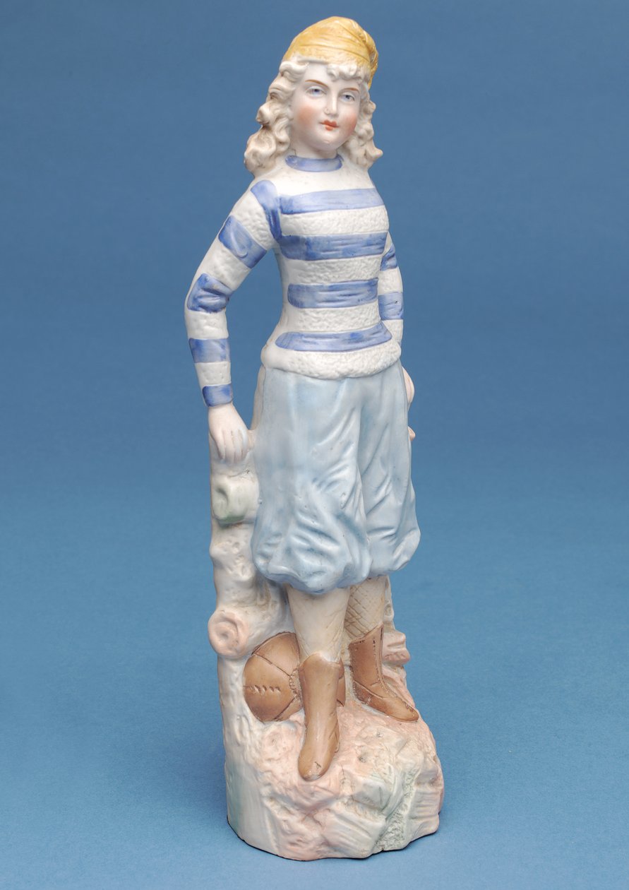 Bisquefigur av en jentefotballspiller i blå- og hvitstripet drakt, ca. 1890-tallet (keramikk) av English School