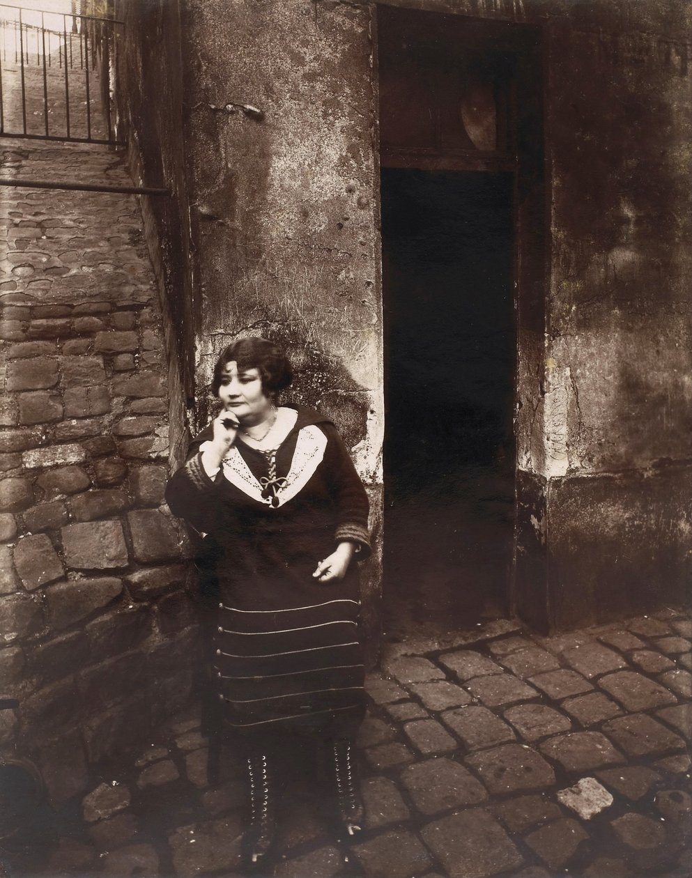 La Villette. Rue Asselin, prostituert som venter foran døren hennes av Eugène Atget