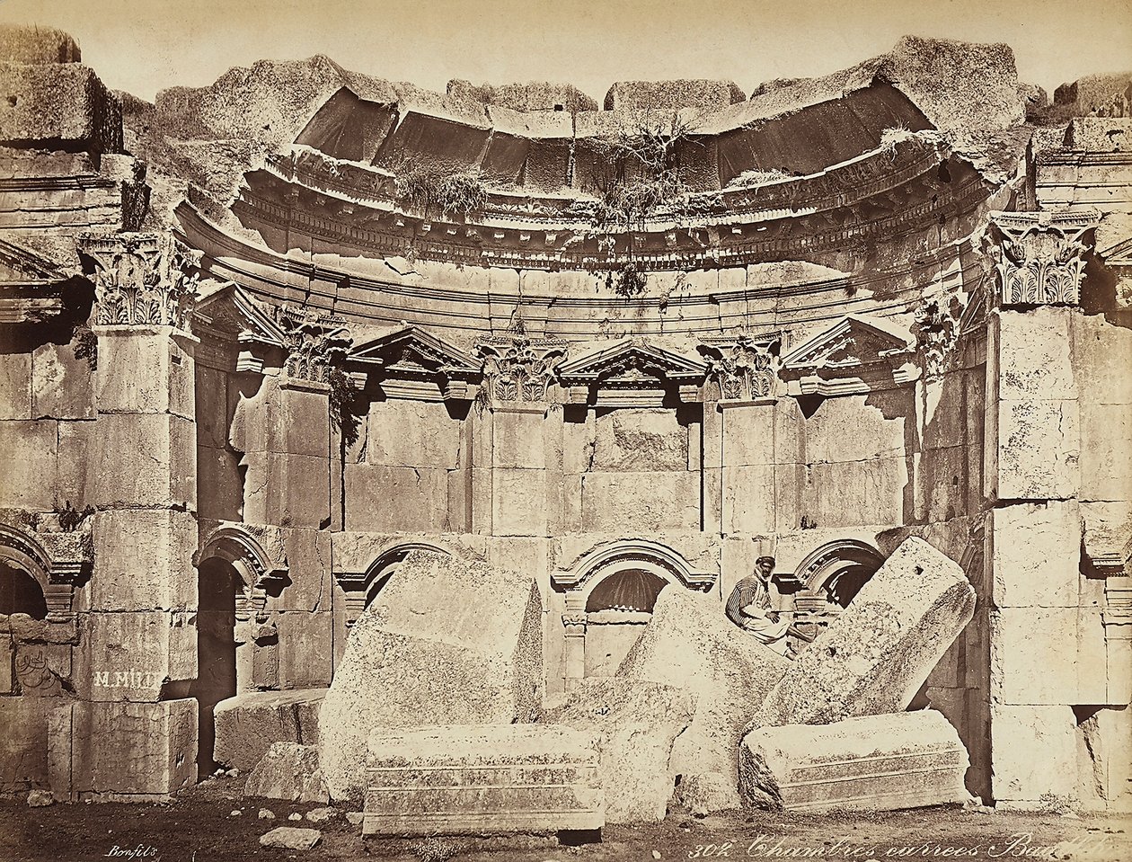 Detalj av de såkalte "rommene" i den arkeologiske sonen Heliopolis eller Baalbek, gammel syrisk by, nå Libanon. En mann poserer, sittende på ruinene av Félix Bonfils