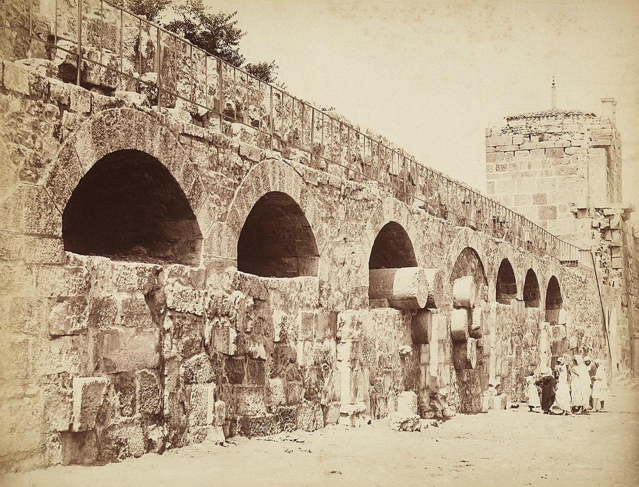 Utsikt over bymurene til Heliopolis eller Baalbek, den gamle syriske byen, nå Libanon. En gruppe mennesker er samlet tett inntil veggen av Félix Bonfils