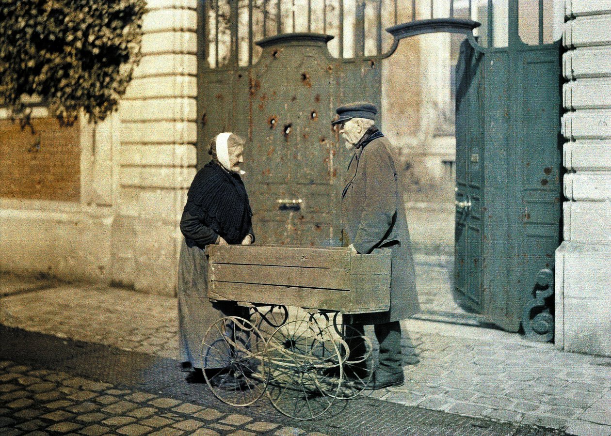 To pensjonister fra Reims, en gammel kvinne og herr Reiser, stående foran en port med mange kulehull, Reims, Marne, Frankrike, 1917 (autokrom) av Fernand Cuville