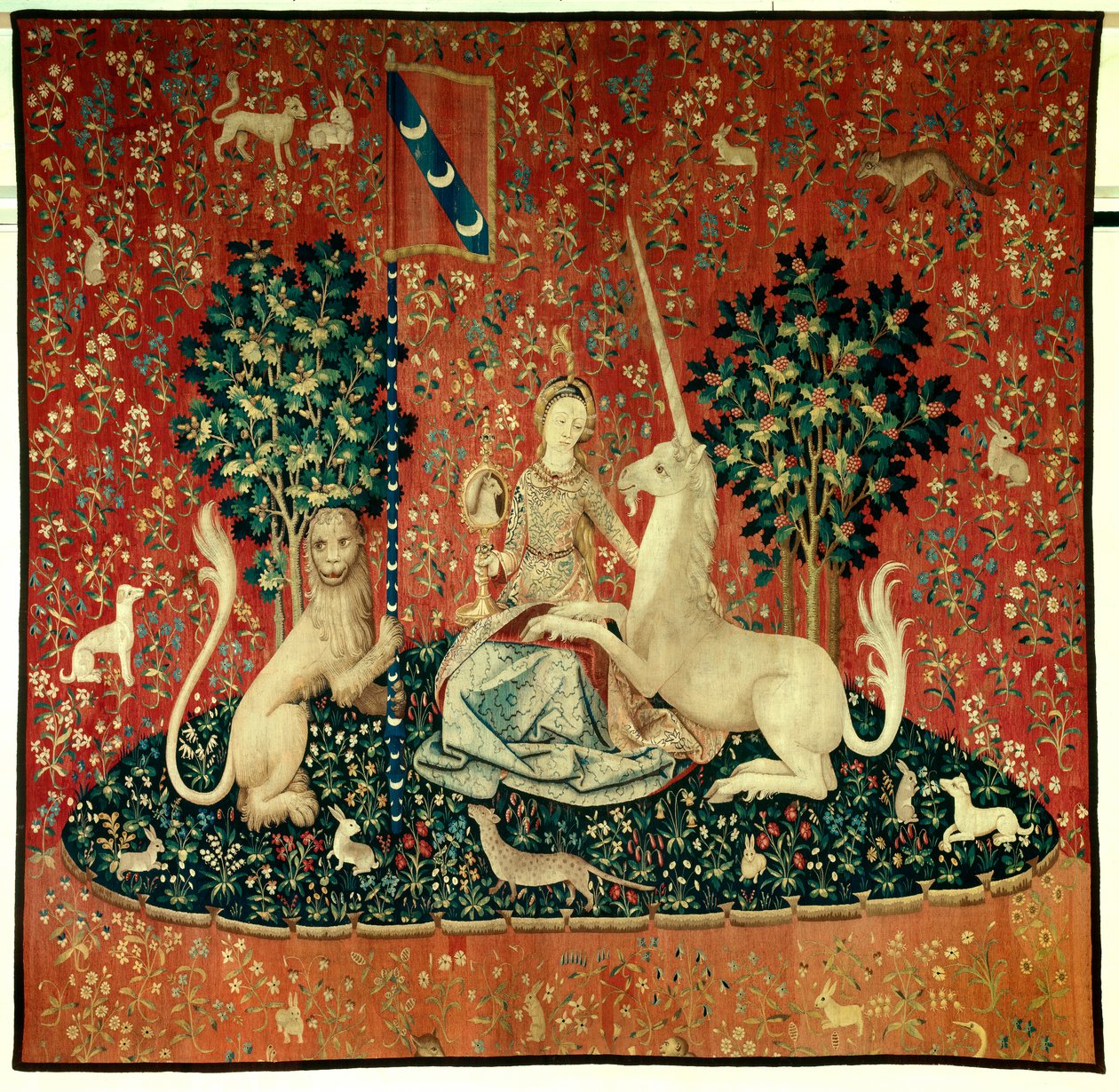 Curtain of the Lady of the Unicorn (Lady of the Unicorn): utsikten. En ung kvinne som holder et speil omgitt av en løve, en enhjørning, en ape, kaniner. Ull- og silketeppe laget mellom 1484 og 1500. Fra Chateau de Boussac, Creuse. Dim. 3,7x4,7 m. P av Flemish School