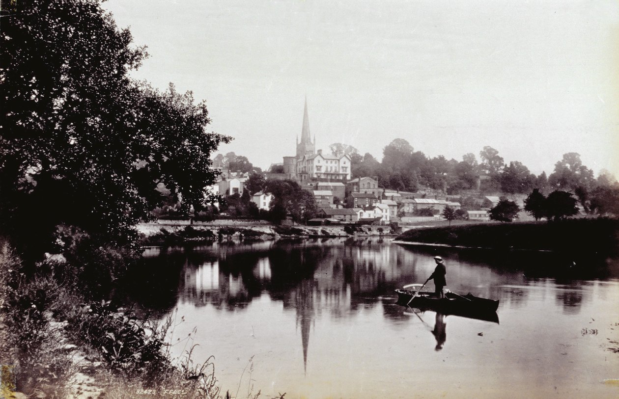 Byen Ross-On-Wye, sett fra en elvebredd. I forgrunnen en mann som står på en robåt av Francis Frith