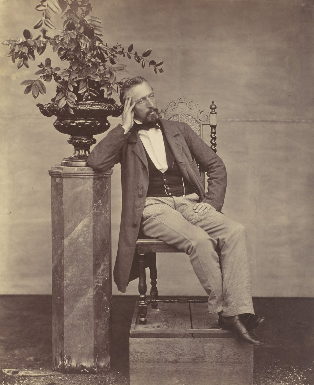 [Mathias Höusermann sittende med albue på pidestall og holder en vase med blomster], 1850-60-tallet. av Franz Antoine
