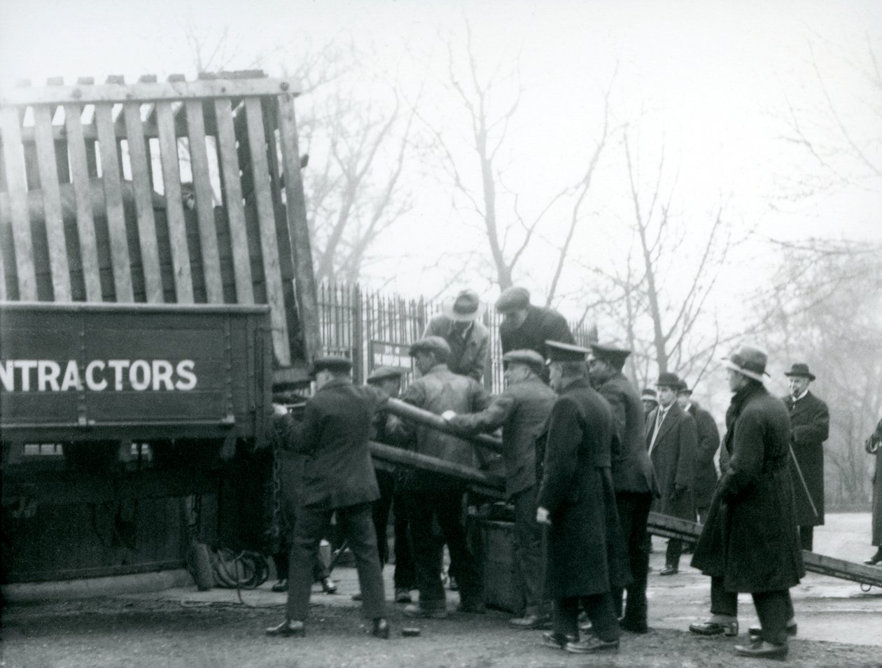 En mengde tilskuere står ved mens et neshorn blir losset fra en lastebil, av voktere, ved London Zoo i 1924 av Frederick William Bond