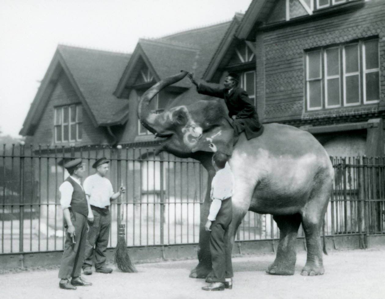 En dekorert indisk elefant, med tre voktere og trener, utenfor Elephant House i London Zoo i 1927 av Frederick William Bond