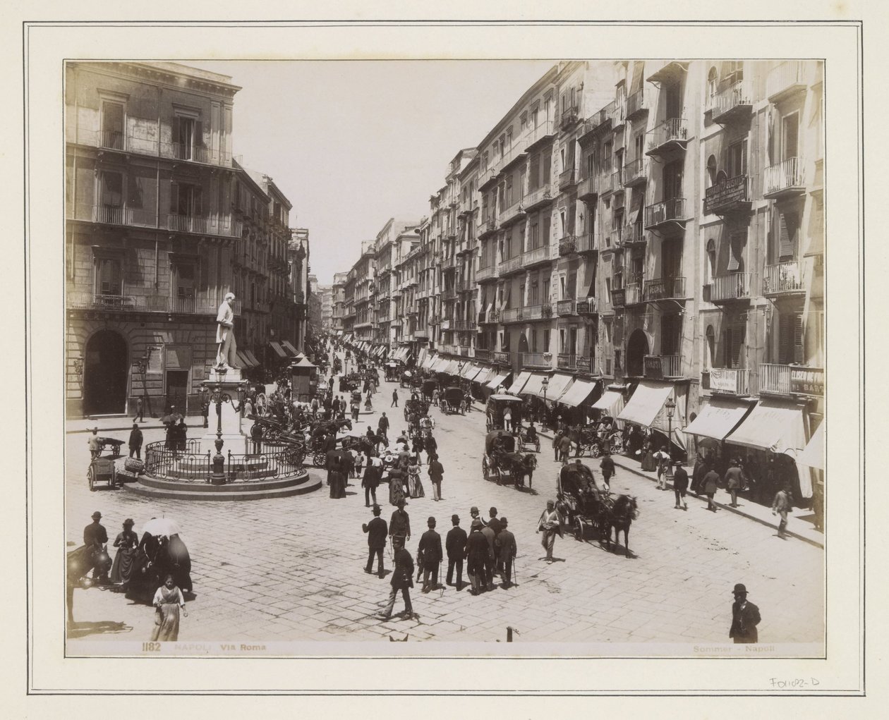 Utsikt over Via Roma i Napoli med en statue, butikker, hestevogner og forbipasserende av Giorgio Sommer