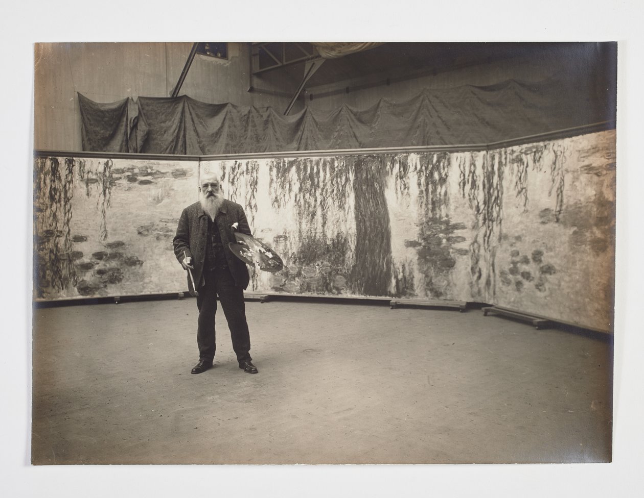 Claude Monet med sin palett foran verket «Les nymphéas» av Henri (attr. to) Manuel