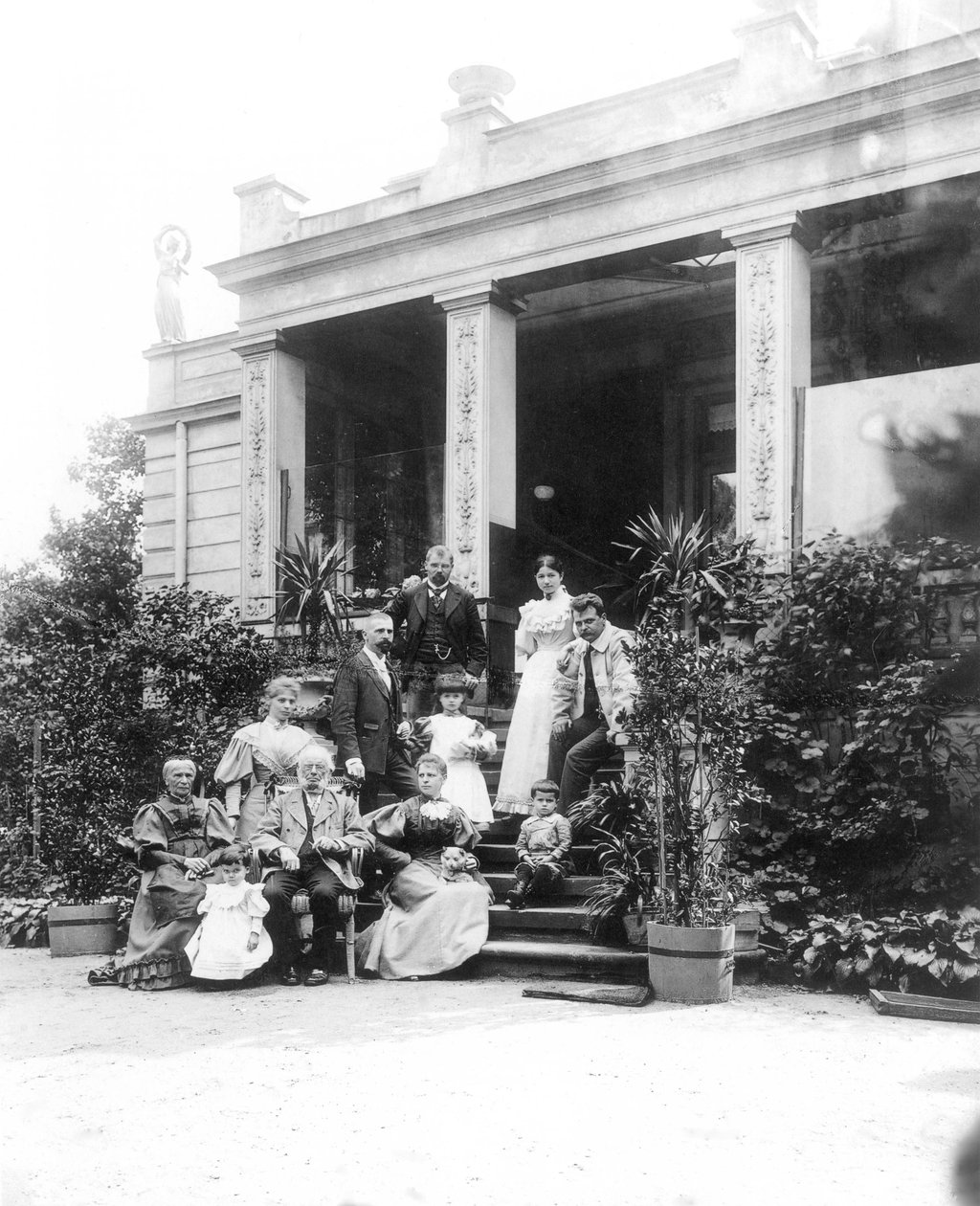 Max Klinger (1857—1920, på bildet øverst til venstre) med familien foran huset til foreldrene i Leipzig, Karl-Heine-Strasse 2 (hageside) av Hermann Walter