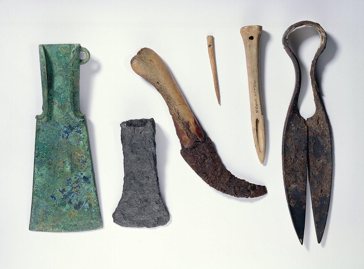Utvalg av verktøy: L-R: bronseøks fra tidlig jernalder med bøyde vinger; senere jernøks; kniv med beinhåndtak; bein nål; bein syl; jernskjær av Iron Age