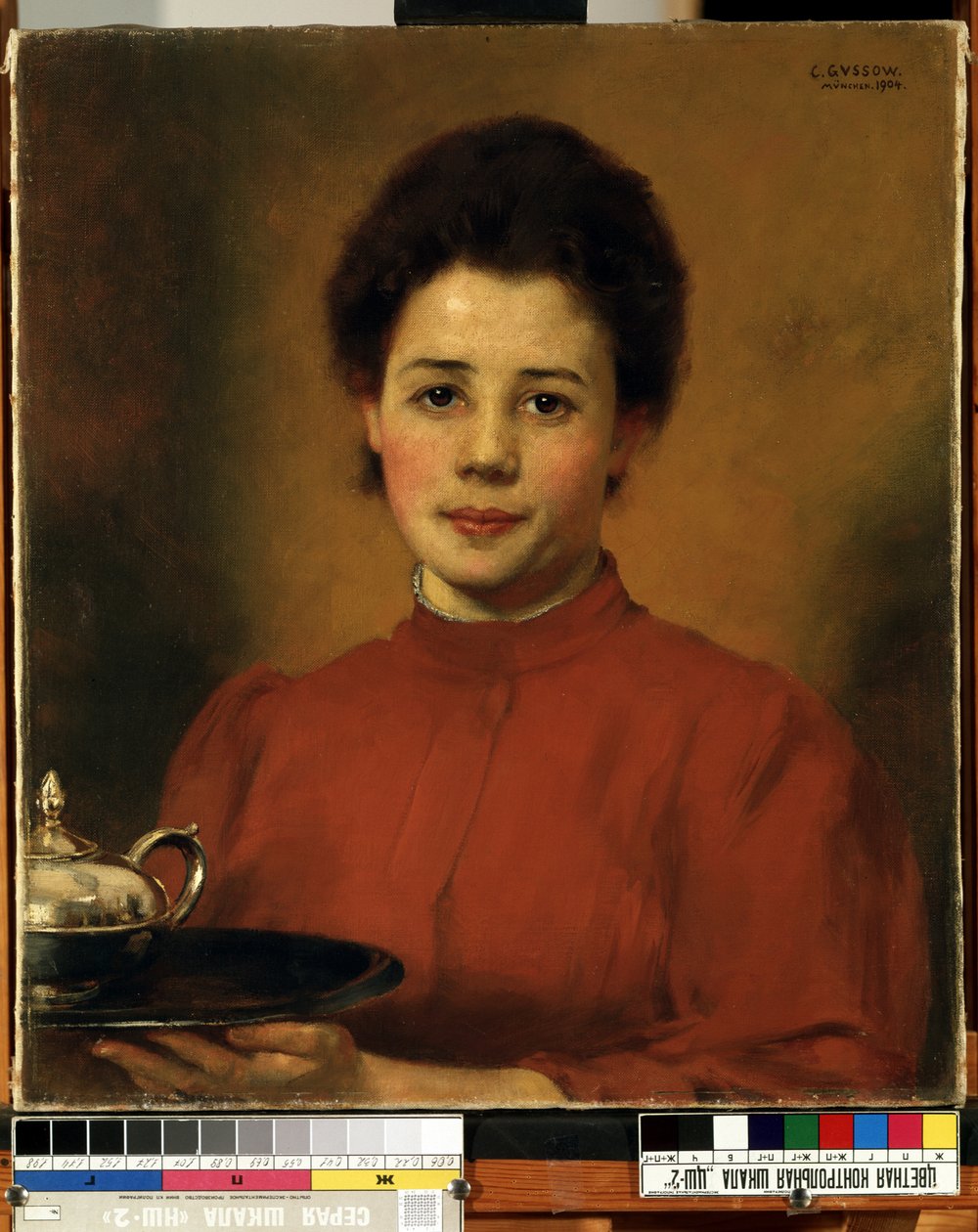 ""Ung kvinne i rødt"" Portrett av en kvinne som bærer et brett med en sølvtekanne. (En kvinne i rødt) Maleri av Karl (Carl) Gusov (1843-1907) 1904 Mikalojus Konstantinas Ciurlionis Fine Arts Museum, Kaunas, Litauen av Karl Gussow