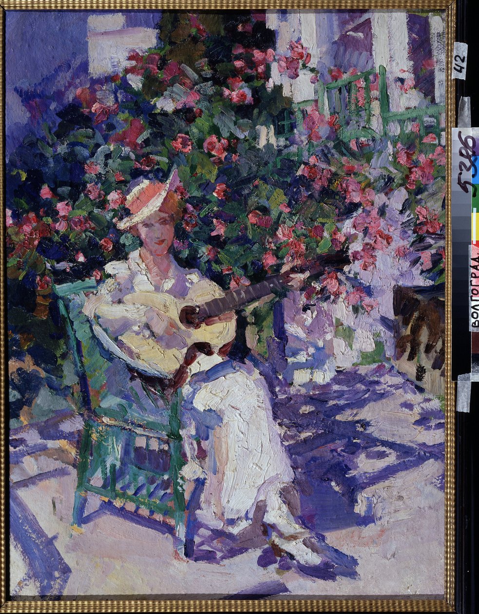 På Krim (På Krim). En ung kvinne i en lett, lett kjole, som sitter på en hagestol, foran en blomstrende lund, spiller gitar, midt på sommeren i kystregionen i Krimbukta. Maleri av Konstantin Alexeyevich Korovin (Constan av Konstantin Alekseevich Korovin