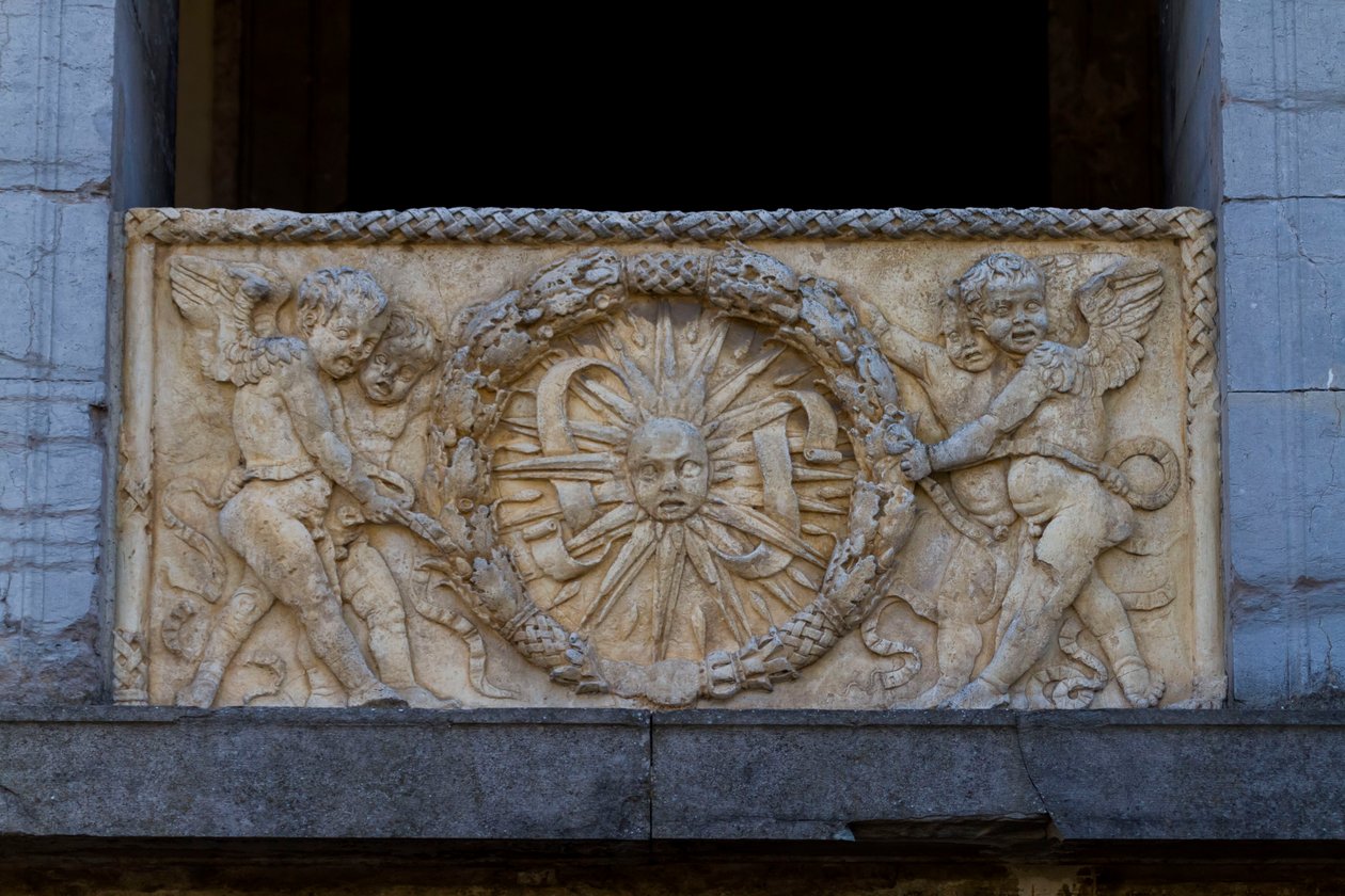 Balustradeplate med strålende sol i krans, basrelieff på fasaden til San Sebastiano-kirken av Leon Battista Alberti