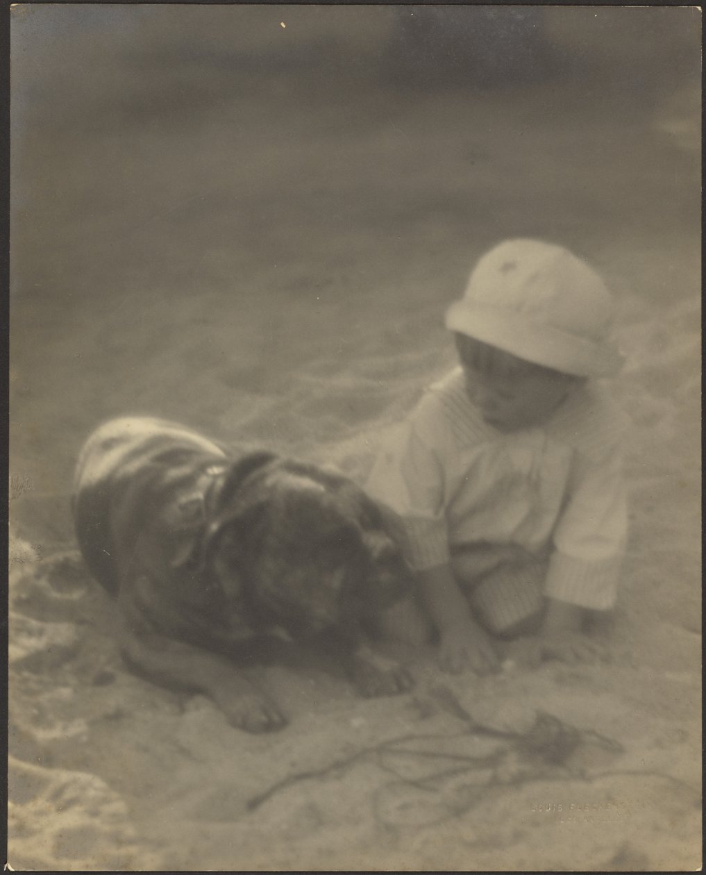 [Gutt som sitter sammen med en hund] av Louis Fleckenstein