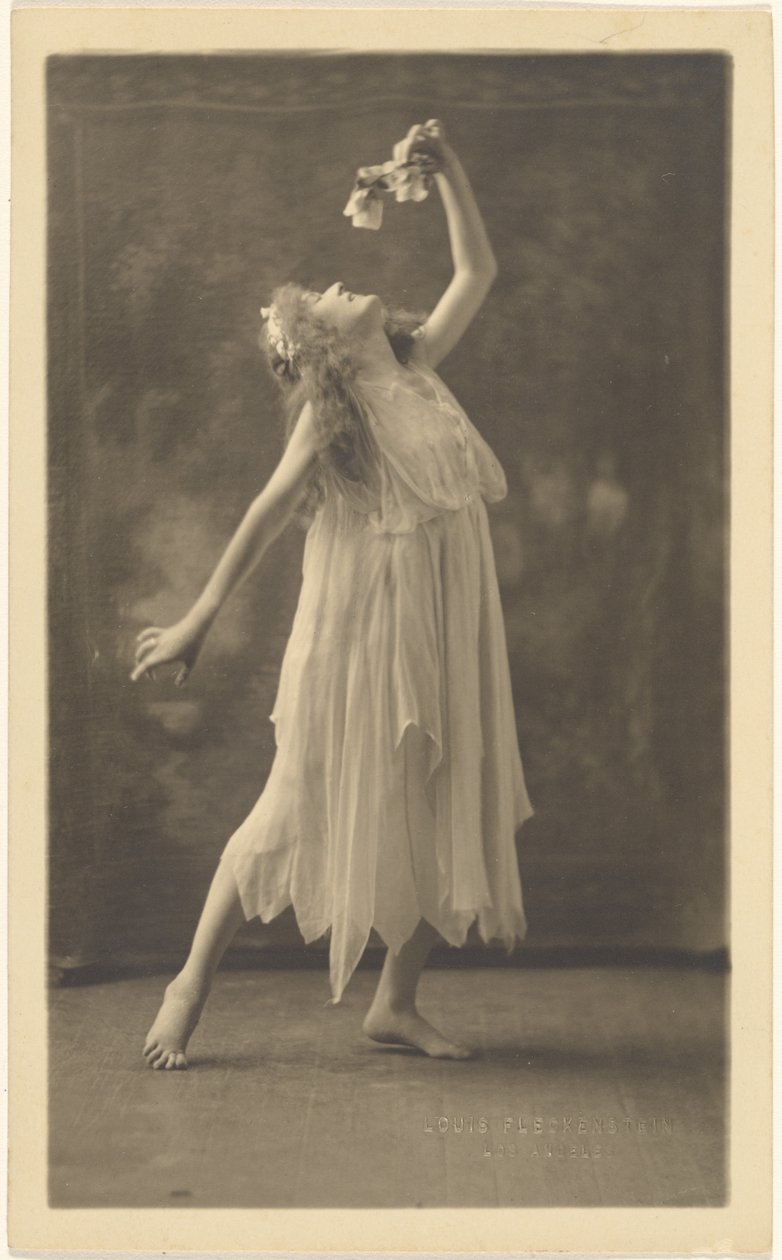 [Kvinnelig danser med blomst foran et veggteppe] av Louis Fleckenstein