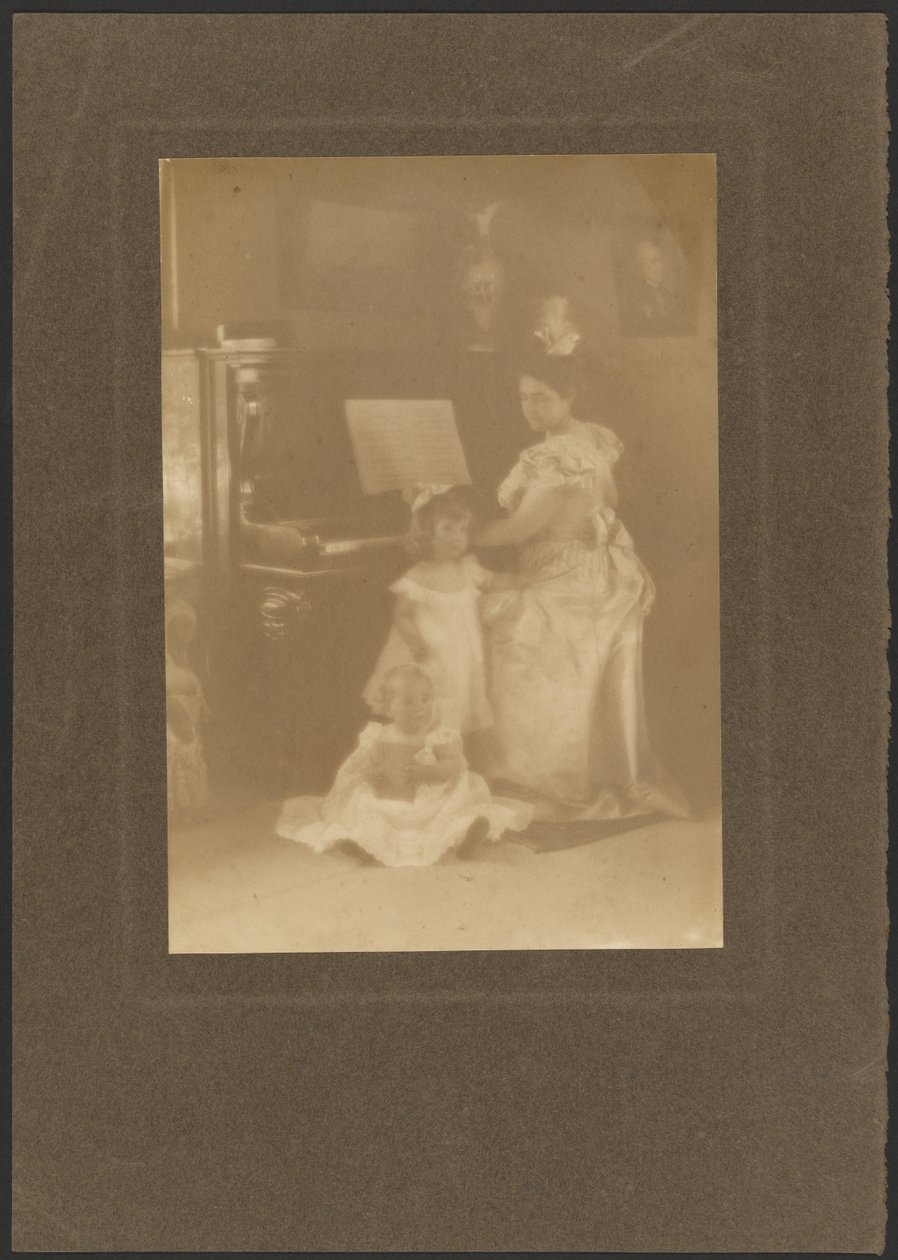 [Kvinne ved et piano sammen med barn] av Louis Fleckenstein