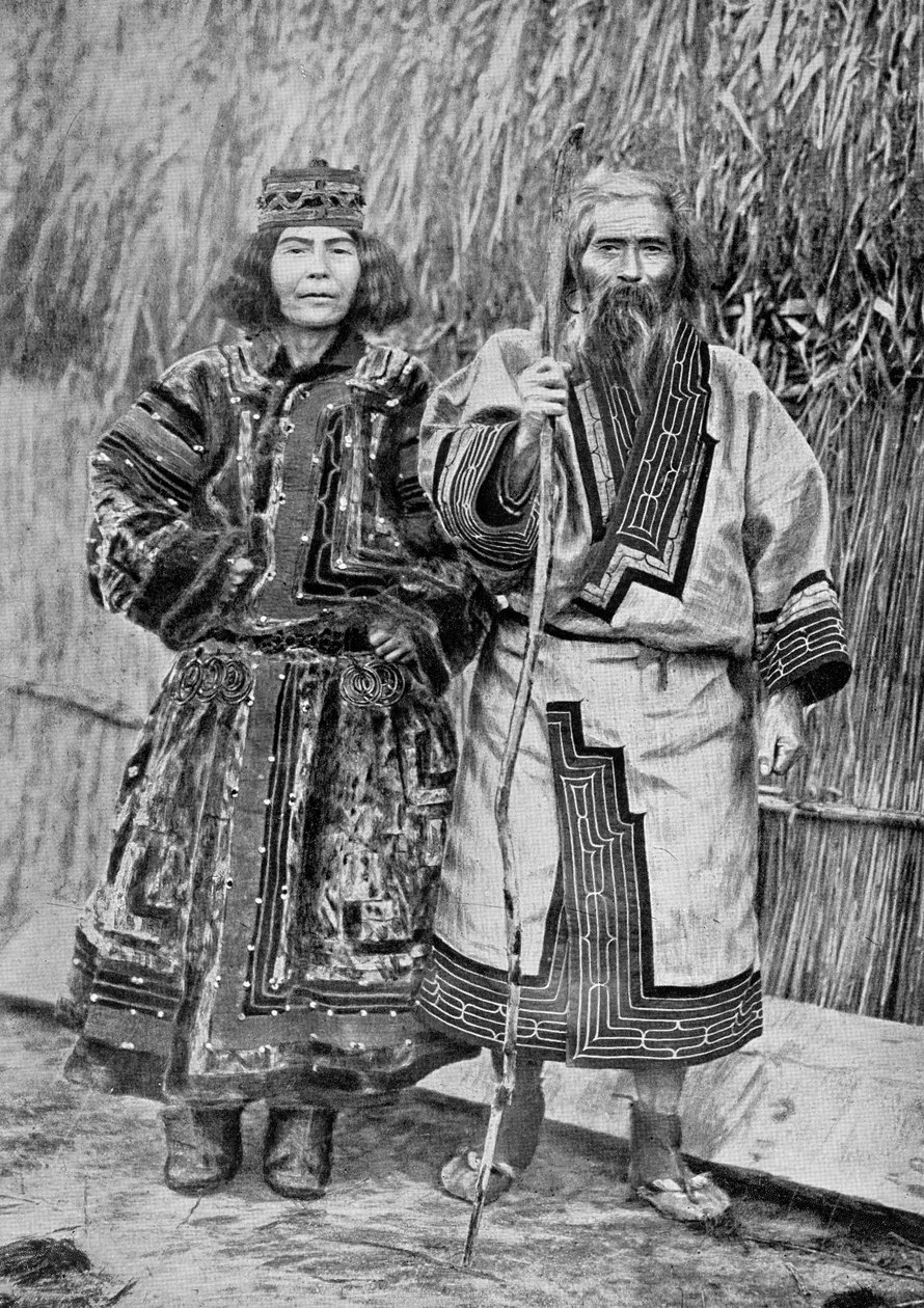 Ainu-par utenfor det tradisjonelle Ainu-hjemmet til en stråtakhytte, sent på 1800-tallet (bw-bilde) av Messrs. Kajima and Suwo