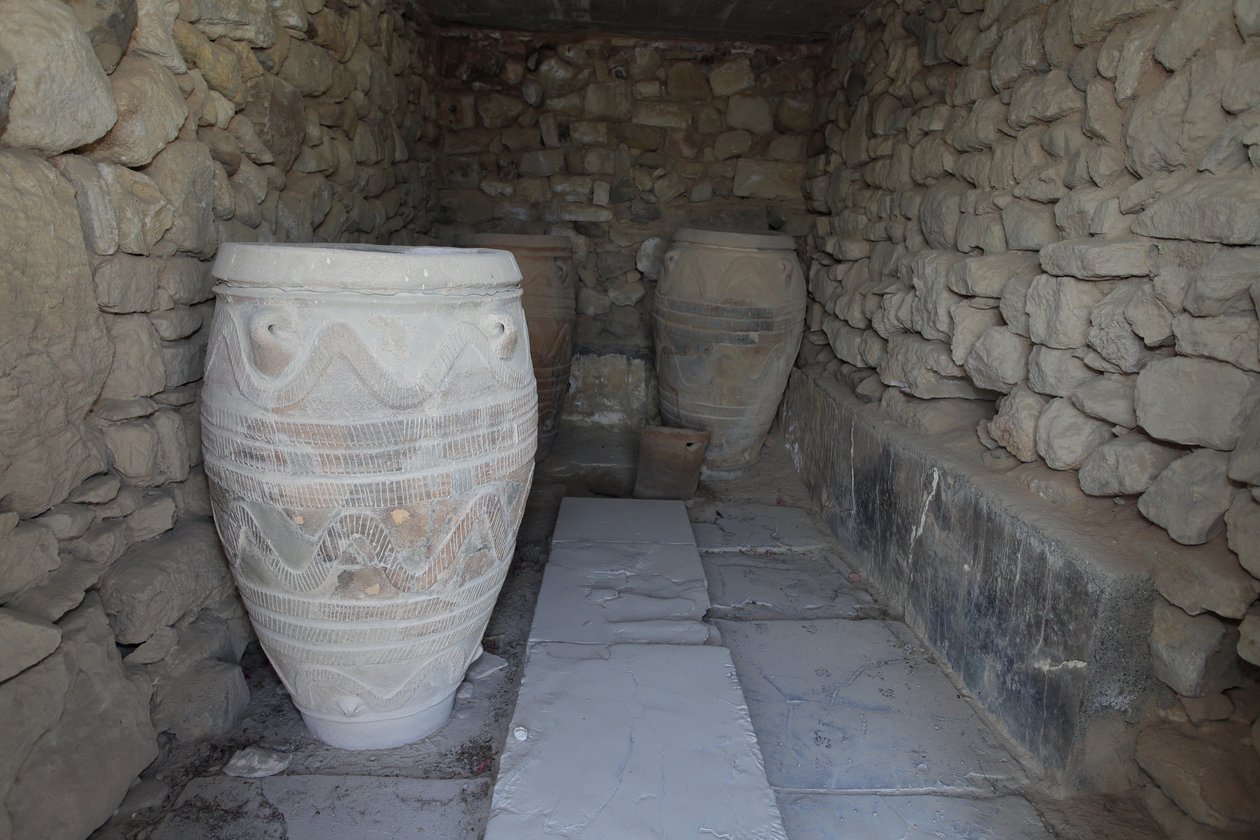 Det minoiske arkeologiske stedet Phaistos. Magasinet til den gigantiske pithoi (lagringskrukker). Disse glassene er dekorert med skive- og taumønster i relieff. av Minoan