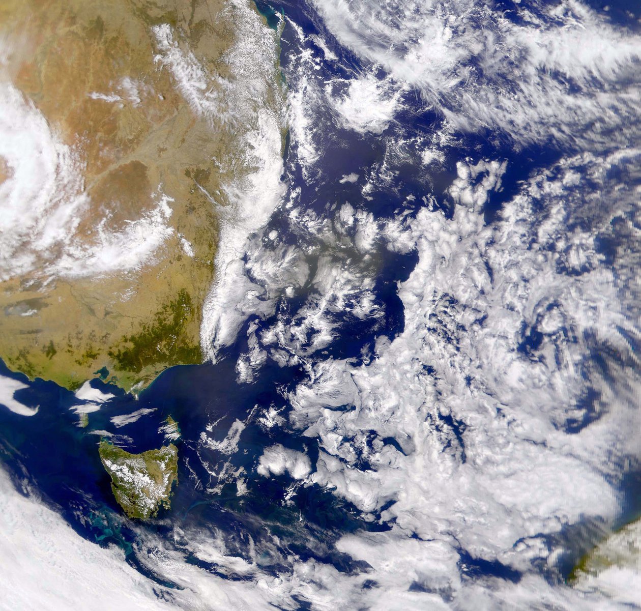 Satellittbilde av Tasmanhavet delvis dekket av skyer. Til venstre er en del av Australia med Tasmania under. NASA. Vitenskap av National Aeronautics and Space Administration National Aeronautics and Space Administration