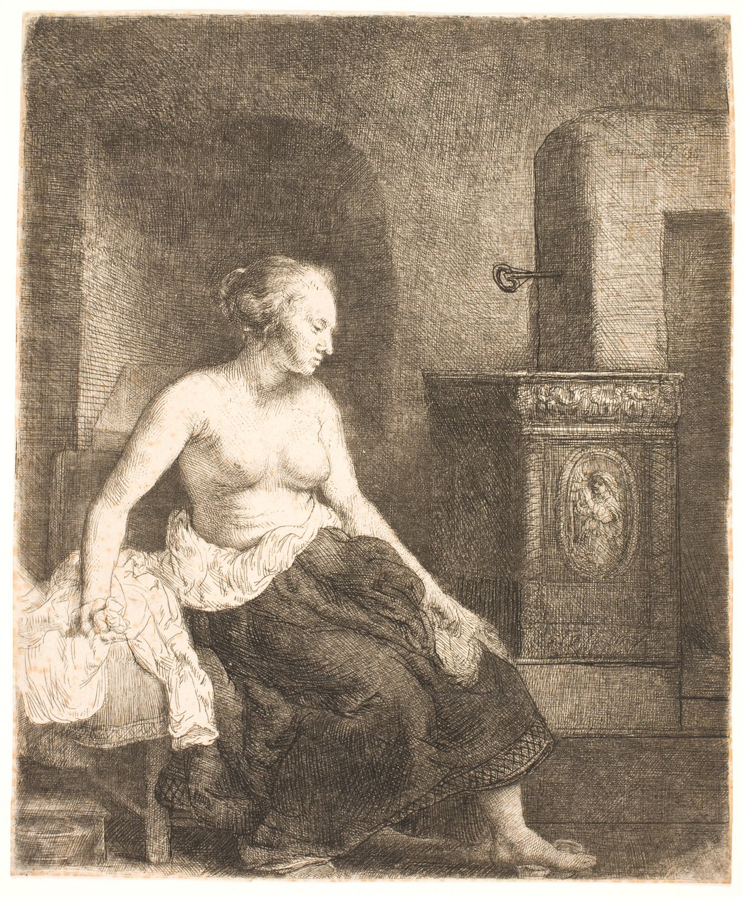 Kvinne som sitter halvkledd ved siden av en komfyr av Rembrandt van Rijn