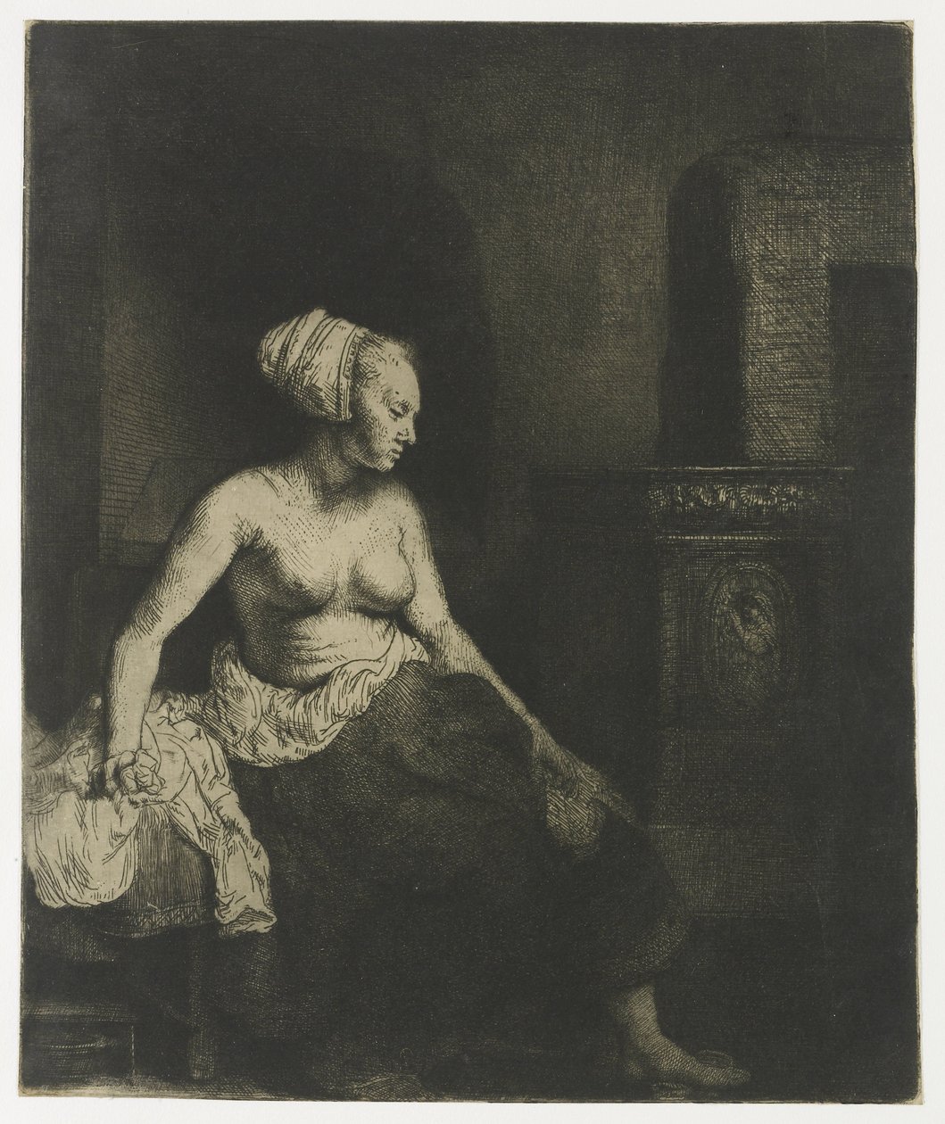 Kvinne som sitter halvkledd ved siden av en komfyr av Rembrandt van Rijn