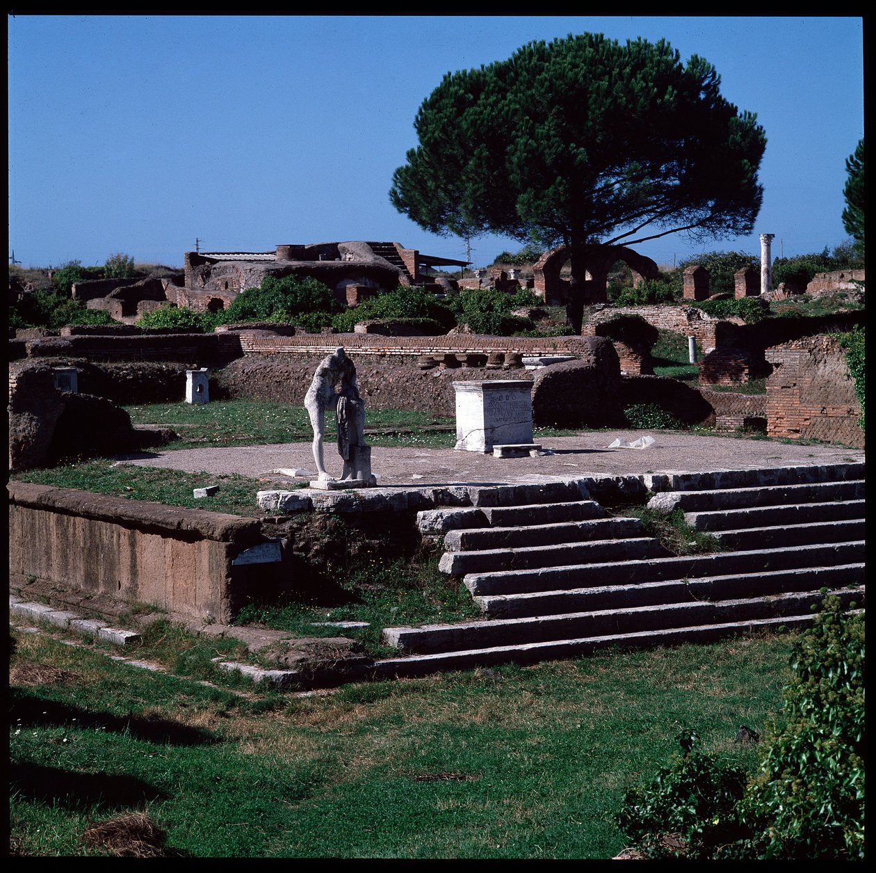 Romersk kunst: utsikt over ruinene av tempelet til Hercules og statuen av Gaius Cartilius Popplicola, borger av Ostia av Roman