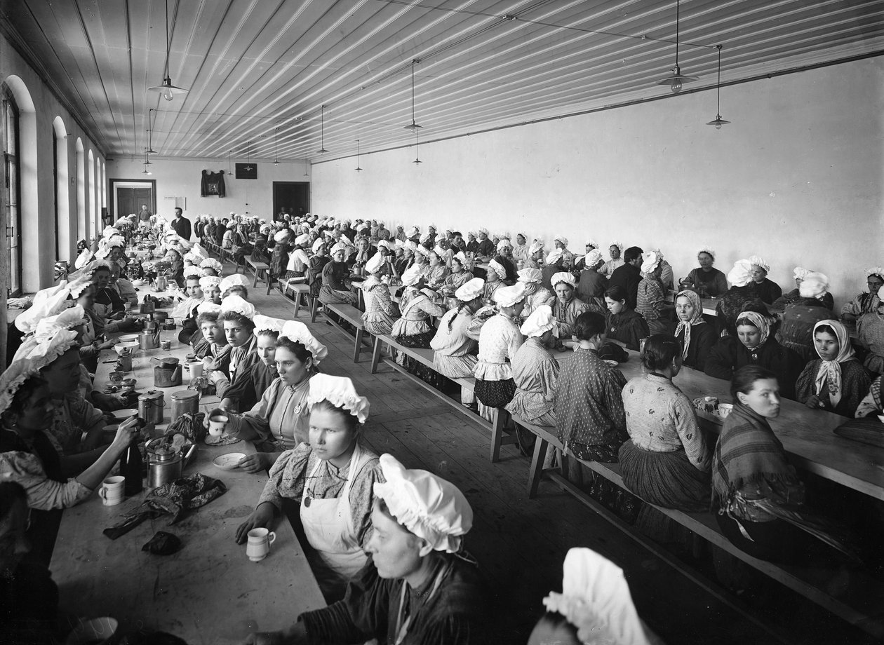 Kvinnelige arbeidere i et fabrikklager tar en middagspause under tilsyn av noen få mannlige tilsynsmenn av Russian Photographer