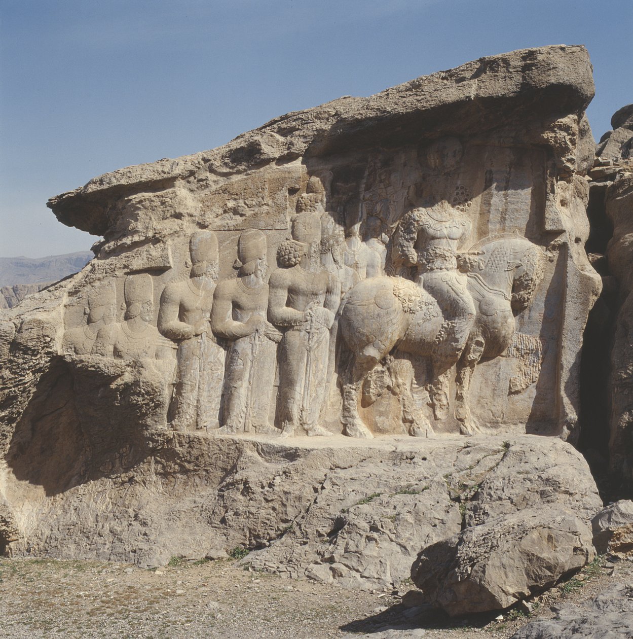 Bergrelieff som viser Shapur I (241–72 e.Kr.) og hans familie med heraldiske emblemer på hattene, med en trespråklig inskripsjon på hesten på gresk, parthisk og mellompersisk av Sasanian