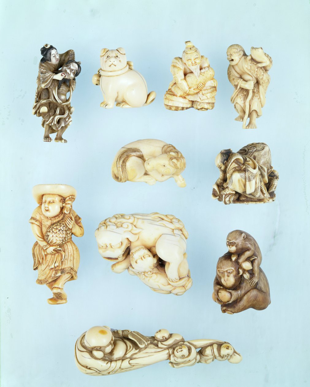 Utvalg av netsuke: Ikkuha Sennin som bærer skjøgen fra Benares; sittende valp; Abe no Yasuneri holder en baby; Gamma Sennin; liggende hest; kriger underkuer en løpsk okse; stående nederlender som holder en langhalehane; sittende ape som holder en fersken-b av Japanese School