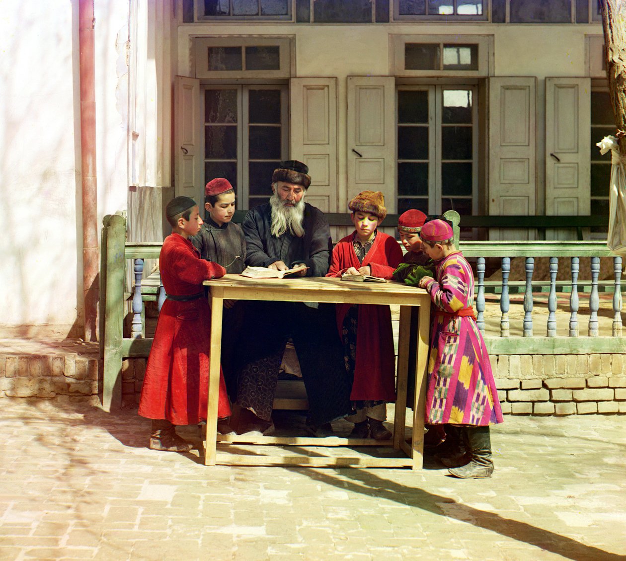 En gruppe jødiske barn med en lærer på et bord foran et hus, Samarkand, det russiske imperiet, mellom 1905 og 1915 av Sergey Prokudin Gorsky
