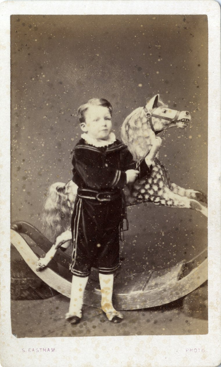 Ung gutt som står ved en gyngehest av Silas Eastham