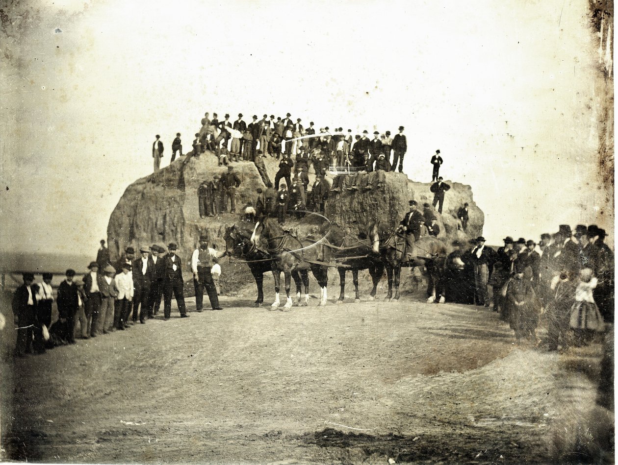 En mengde menn, barn og noen få hester står på toppen av og foran Big Mound, som er vist delvis gradert av Thomas M. Easterly