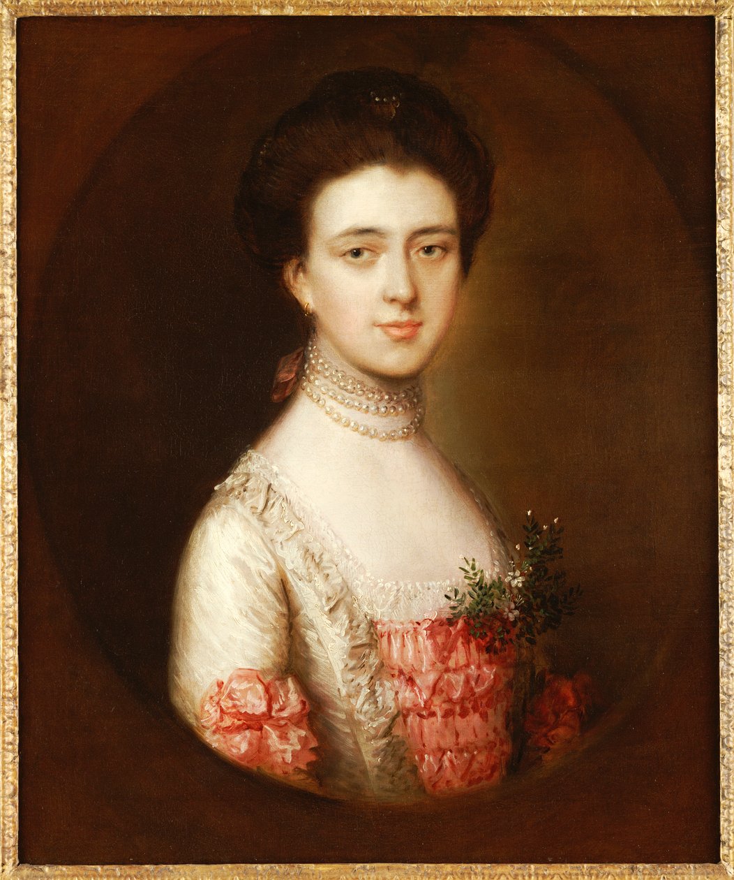 Portrett av en dame, bystelengde, i en rosa og hvit kjole trimmet med blonder og et perlekjede av Thomas Gainsborough