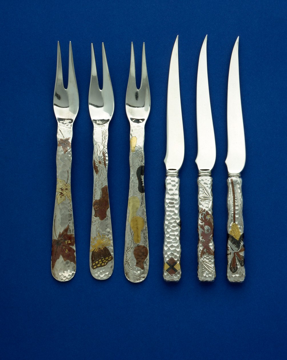 En del av et fint og sjeldent sett med 36 dessertkniver og -gafler, spothamrede håndtak innlagt med patinert kobber og varifarget gull, med graverte detaljer av forskjellige blomster-, dyre- og geometriske design, ca. 1880 (kobber, gull) av Tiffany and Company