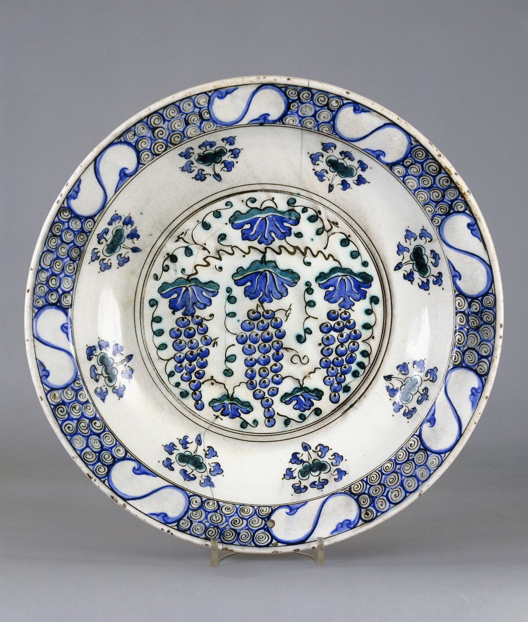 En Iznik keramikkfat, med en sentral runddel som viser tre klaser med druer og vinblader, ca. 1570 (keramikk) av Turkish School
