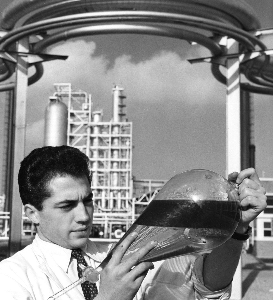 En laboratoriearbeider holder en skilletrakt med olje, raffineriet i Dunkirk, Frankrike, 1950-tallet av Unbekannt
