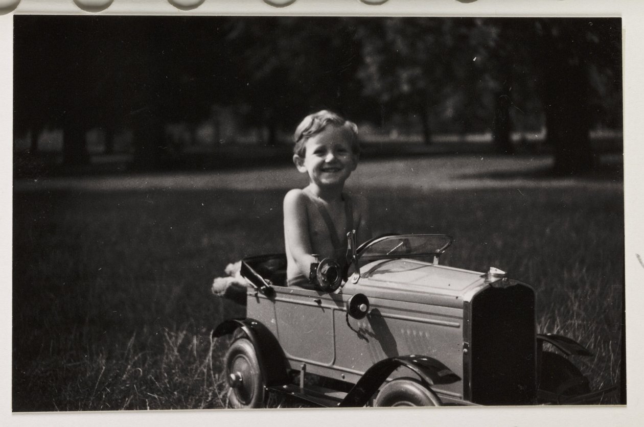 Gutt kjører en leketøypedalbil, ca 1930 av Unbekannt