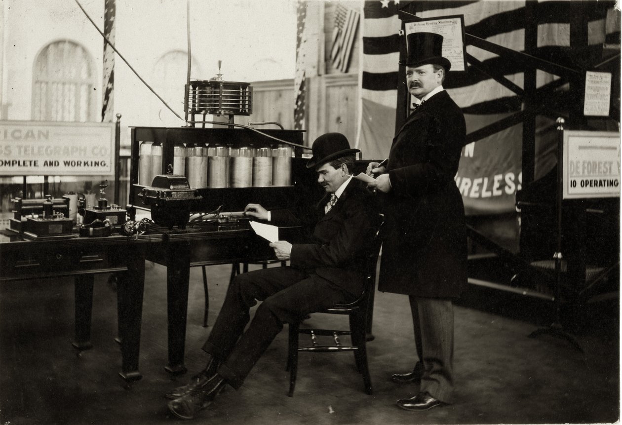 Lee DeForest (sittende) sender en trådløs telefonmelding i Department of Electricity på verdensutstillingen i 1904 av Unbekannt