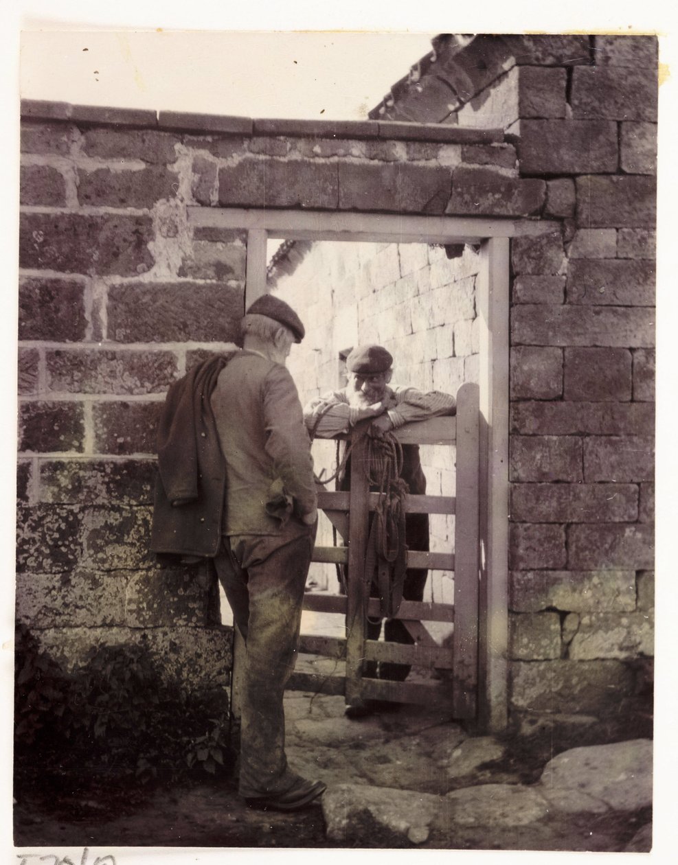 To menn snakker over en port, ca 1905 av Unbekannt
