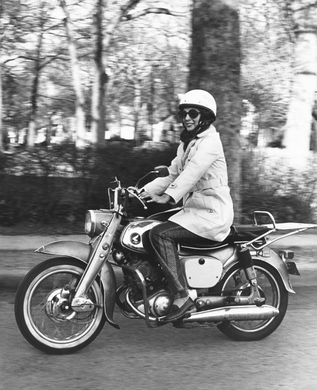 USA: ca. 1961 En kvinne som kjører på sin Honda 160-motorsykkel. (s/hvitt bilde) av Unbekannt