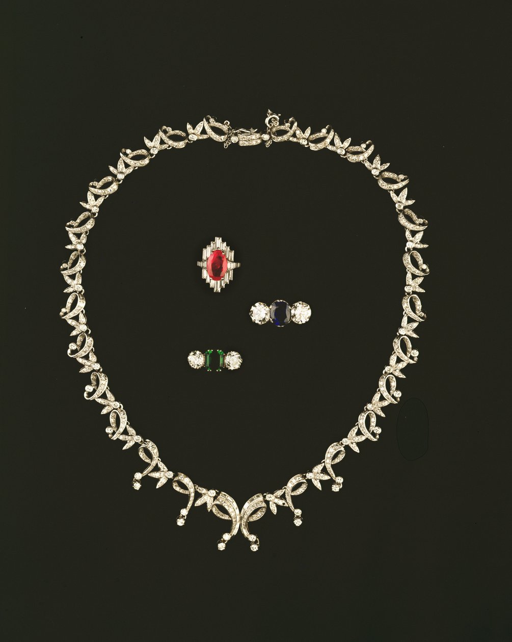 Art Deco rulle- og bladdesignkjede; rubin og diamant baguette klynge ring; safir og diamant tre stein ring; smaragd og diamant tresteinsring av Unbekannt Unbekannt
