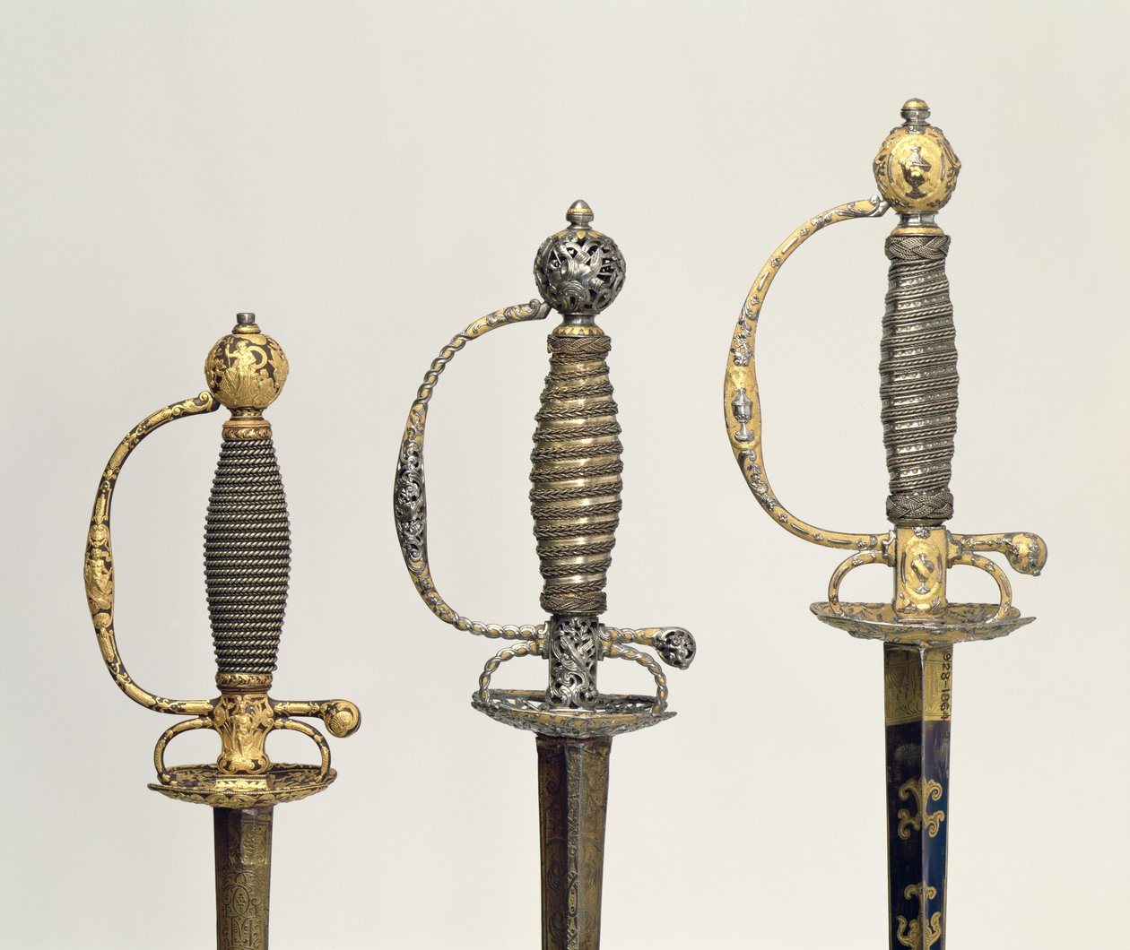 Hilter av tre franske sverd: ett av stål, blånet og belagt med design i jaget gull, ca. 1730; en av stål gjennomboret og meislet og slipt av mattet gull, ca. 1760; en av meislet stål, gr av Unbekannt Unbekannt