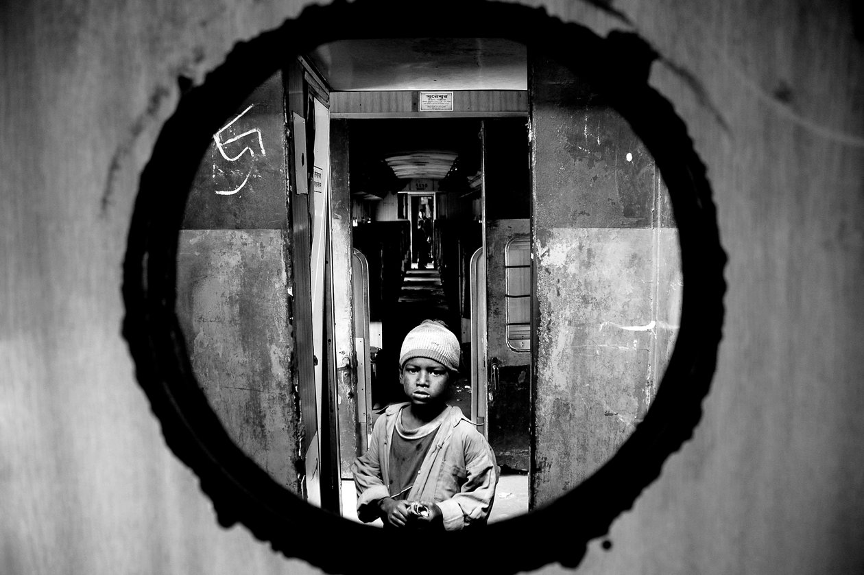 Portrett av et gatebarn sett gjennom dørhullet i kupeen til et tog på Kamalapur jernbanestasjon i Dhaka, Bangladesh. 5. januar 2007. av Unbekannt Unbekannt