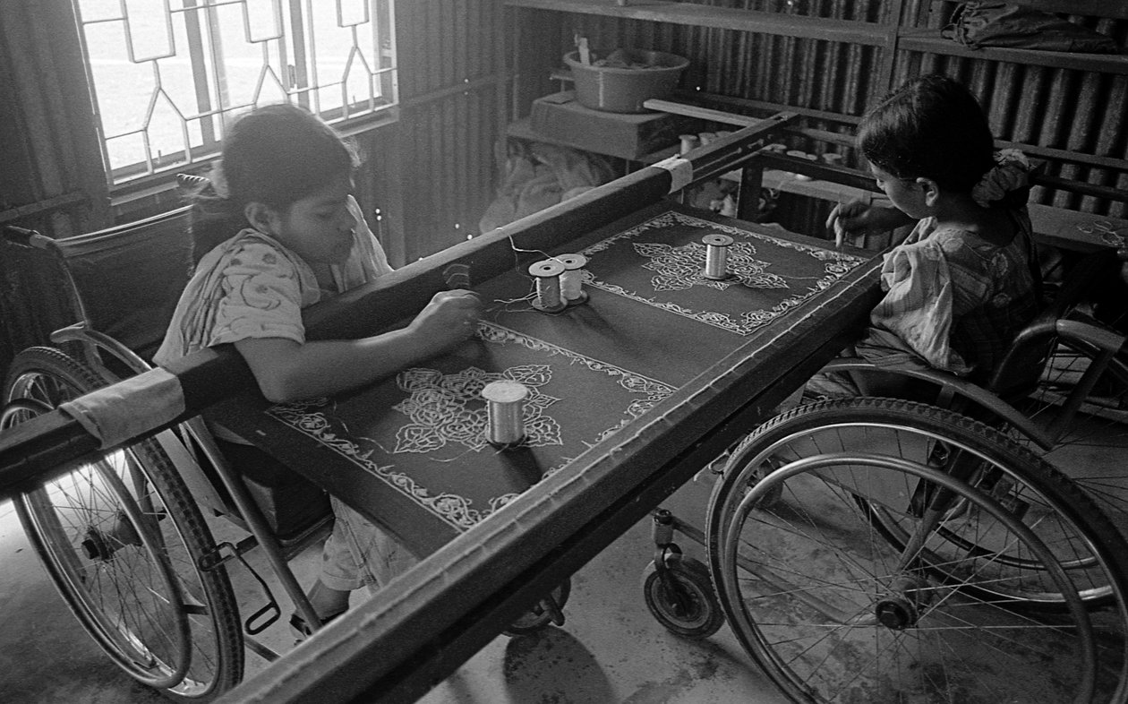 To fysisk utfordrede jenter er engasjert i broderi på klærne ved The Center for the Rehabilitation of the Paralysed, CRP i Savar, Dhaka, Bangladesh. 2005. av Unbekannt Unbekannt