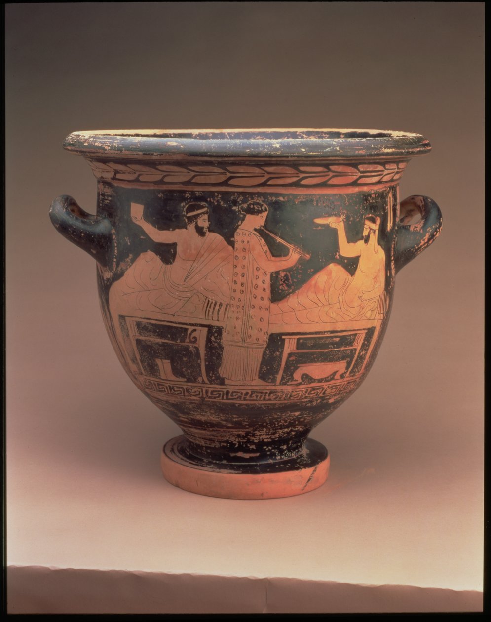 Attisk klokkekrater med røde figurer dekorert med en symposiumscene av to liggende figurer og en stående fløytespiller, gresk, ca. 440-430 f.Kr. (keramikk) av Unbekannt
