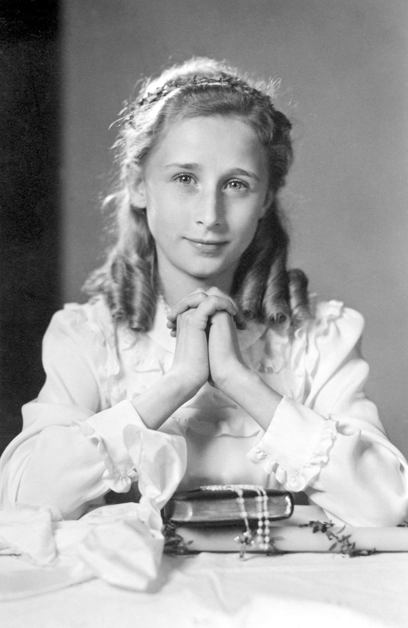Kristen jente med hender sammen i bønnestilling med bibel, rosenkrans og stearinlys (bilde av nattverd). Fotografering rundt 1932 av Unbekannt