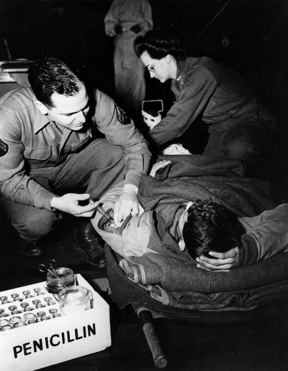 Andre verdenskrig (1939–1945) - Andre verdenskrig (2 eller 2): Luxembourg februar 1945: På et evakueringssykehus fra den amerikanske hæren administrerer en medisiner (sykepleier) penicillin til en skadet soldat for å unngå infeksjon mens en sykepleier forb av Unbekannt