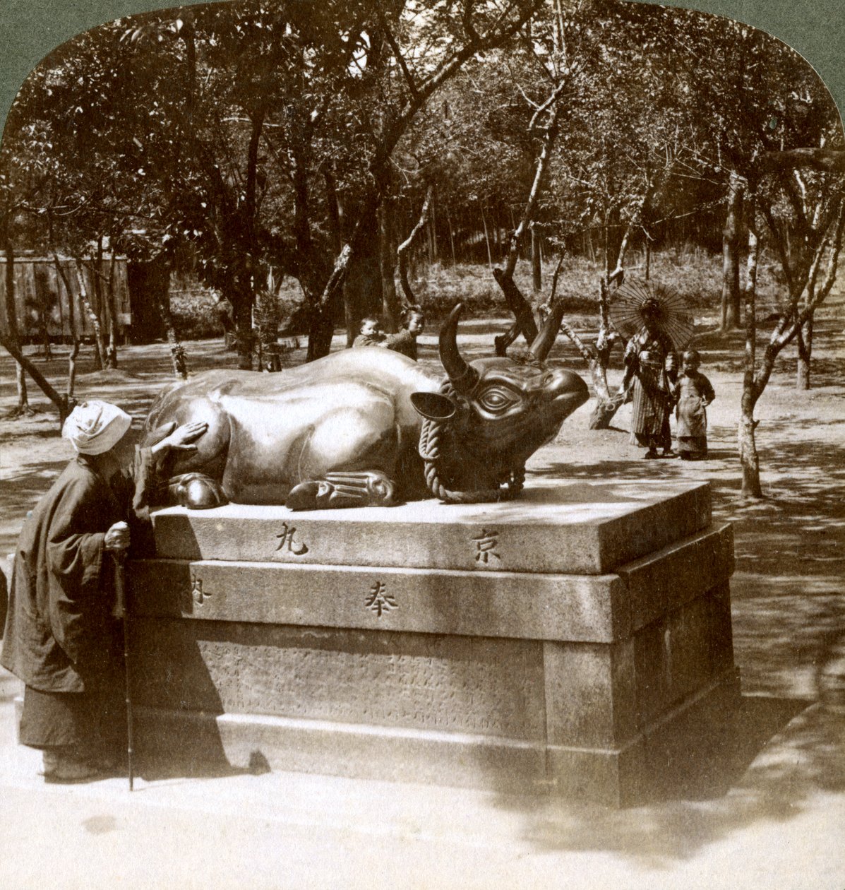Troende kvinne som stryker en bronseokse for å kurere revmatisme, Kitano Tenjin-tempelet, Kyoto, Japan, 1904 av Underwood and Underwood